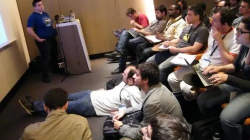 Conf&eacute;rence en salle, participants assis et attentifs.